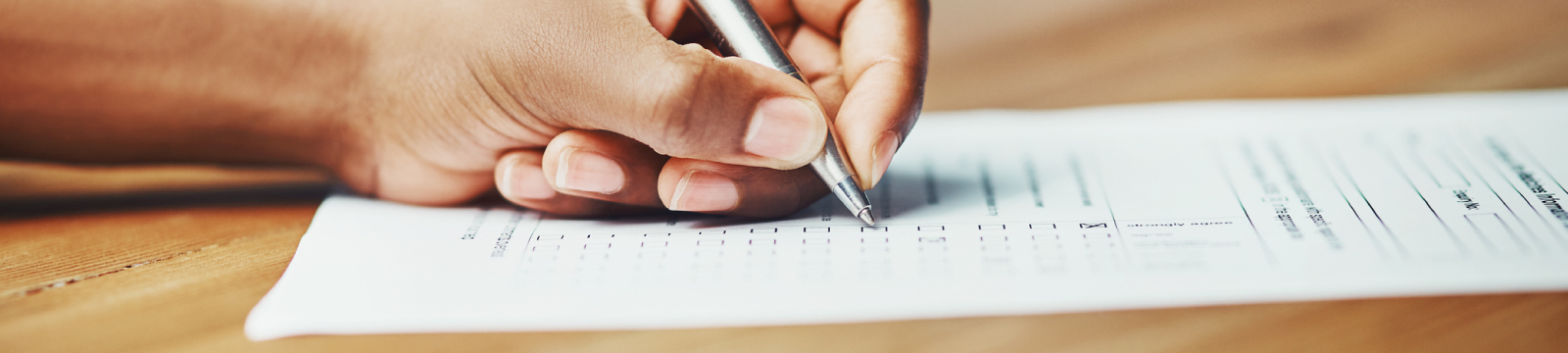 person using pen to fill out a form